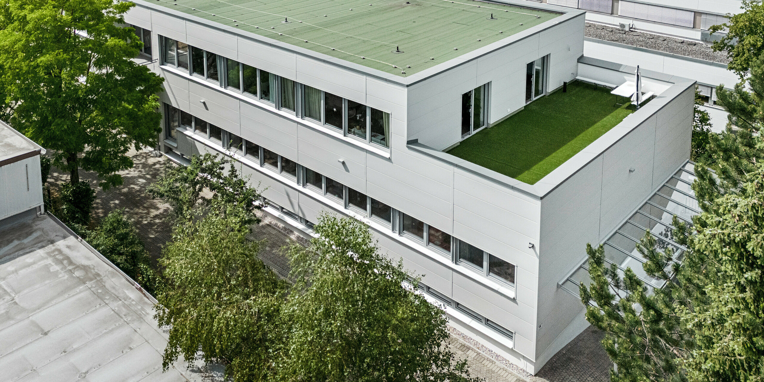 Des Sidings PREFA grand format entourent un bâtiment d'entreprise à Oberschleißheim (Allemagne). Les éléments de façade extra-larges en aluminium ont été choisis dans la couleur blanc Prefa.