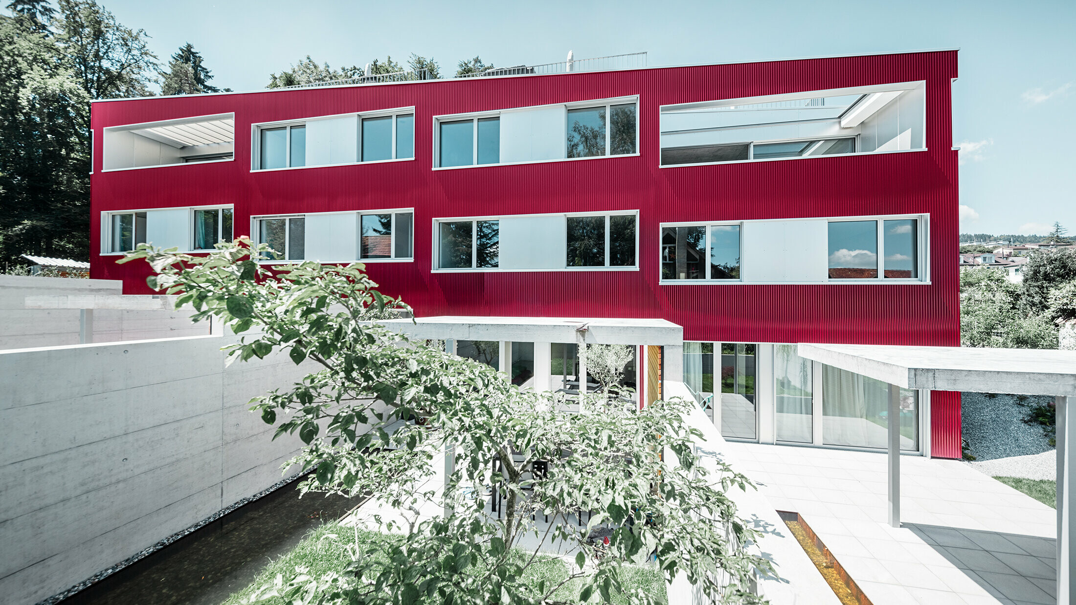 Complexe résidentiel à toit plat et façade de balcons avec profil sinus  bordeaux de PREFA 