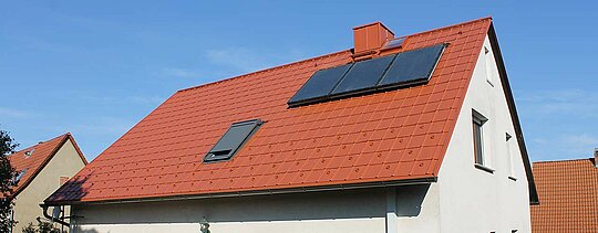 Einfamilienhaus mit Satteldach eingedeckt mit der PREFA Dachplatte in Ziegelrot. Dachfläche inklusive Solaranlage und Dachfenster