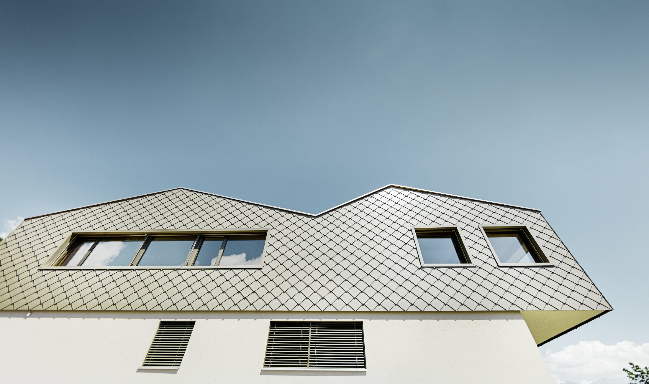 Maison individuelle moderne au milieu des vignobles de la vallée du Rhône avec 4 toits différents et galerie ouverte avec une façade en losanges couleur bronze