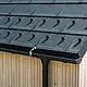 Detailafbeelding van de PREFA dakplaat R.16 met sneeuwstop, dakgoot en afvoerbuis in zwart P.10 incl. bliksembeveiliging en een verticale houten gevel
