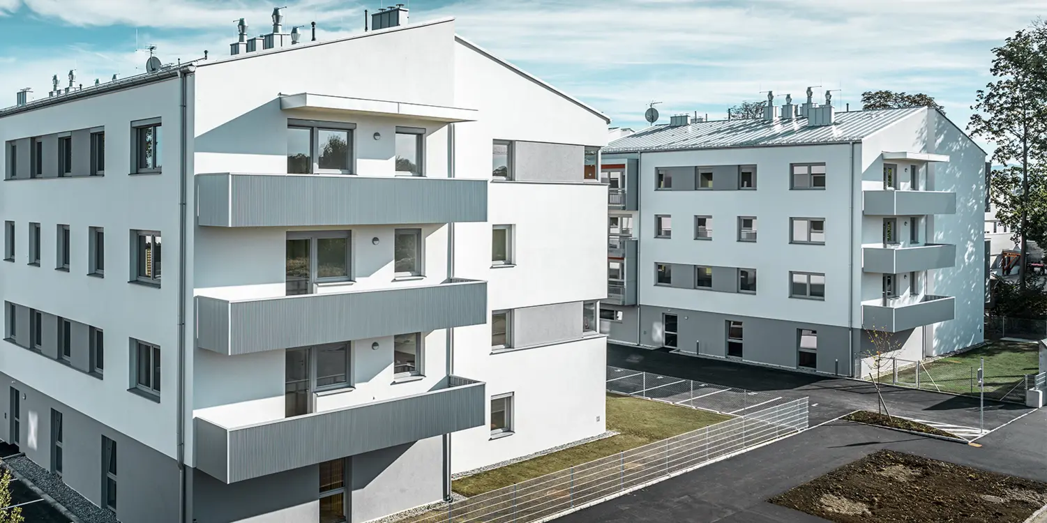 Modern woningcomplex met witte gevel en balkons met PREFA-kartelprofiel in zilvermetallic