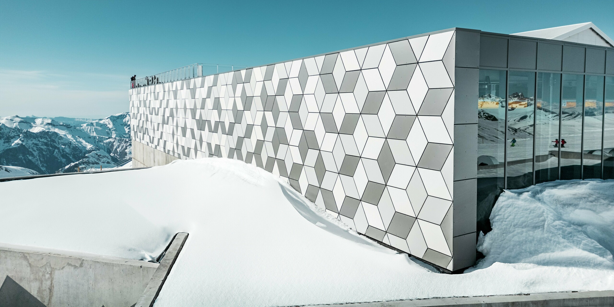 La station supérieure du téléphérique des Deux Alpes arbore une superbe façade en panneaux composites en aluminium PREFABOND disposés en losanges. Les panneaux blancs et gris s'intègrent harmonieusement au paysage montagneux enneigé et reflètent la lumière intense des Alpes. Ce design innovant allie raffinement esthétique et grande résistance aux conditions climatiques extrêmes.