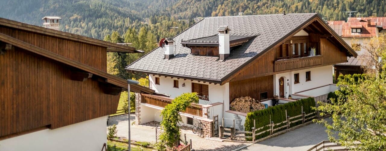 Traditionelles Haus mit nussbrauner PREFA Dacheindeckung und einer Fassade mit Holzelementen und Putz