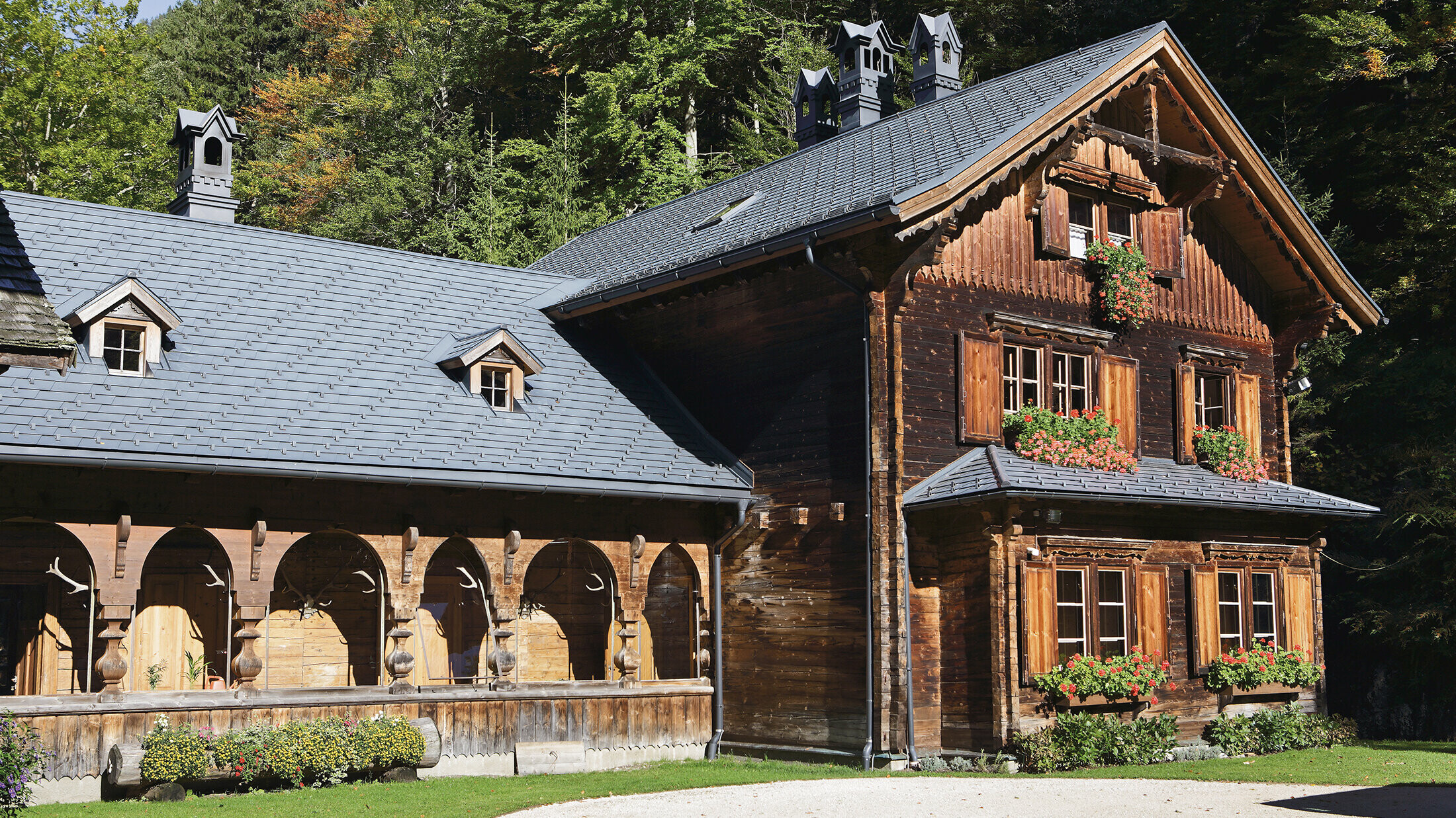 Die rustikale Forst- und Jagdhütte in Gaming bei Langau, gedeckt mit PREFA Dachschindeln in P.10 Anthrazit, umgeben von grüner Natur und Wald.