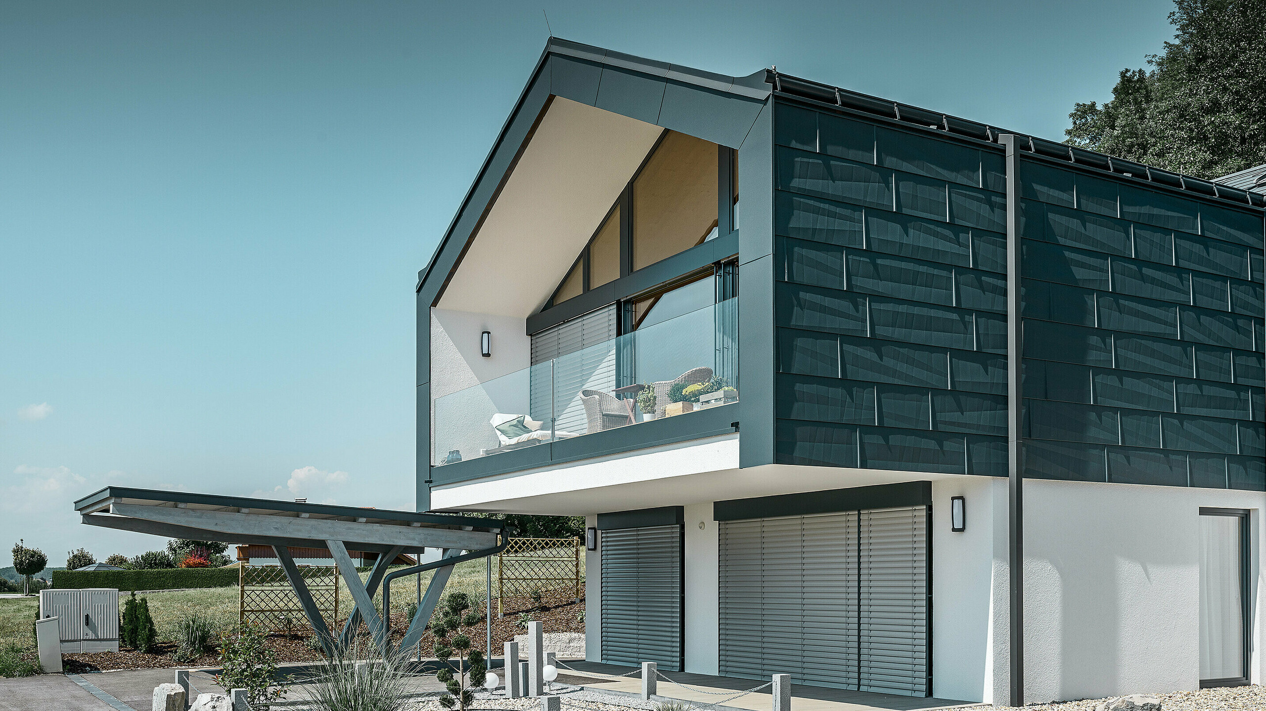 Étage supérieur avec FX.12 couleur P.10 anthracite Revêtement de façade de l’étage supérieur avec le panneau de façade FX.12 PREFA couleur P.10 anthracite. Le solide tuyau de descente carré PREFA vient compléter le tout.