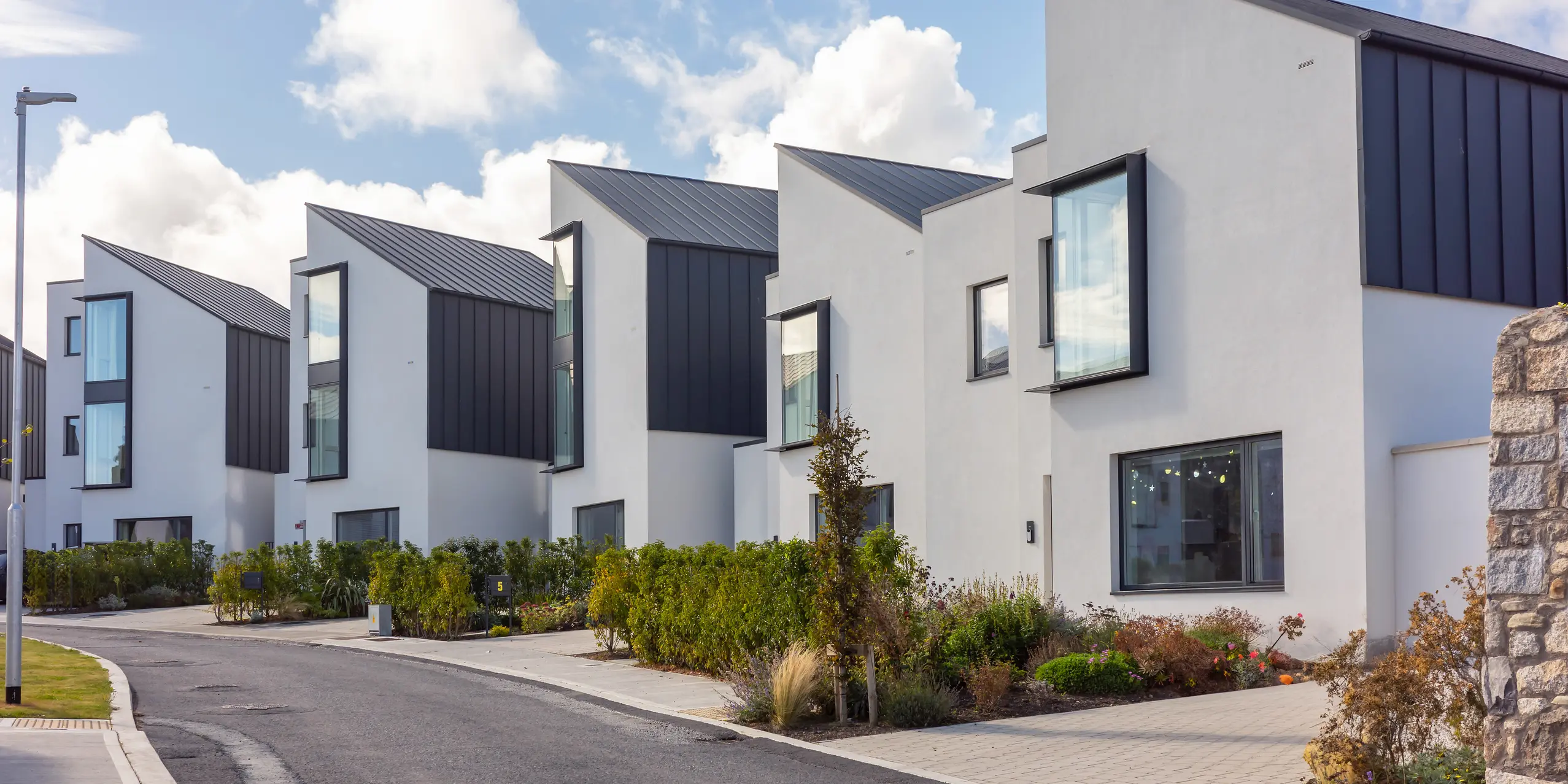 Maisons de ville à Watson Place, à l'architecture épurée et moderne, avec toitures et façades PREFALZ en pente, couleur P.10 anthracite. Les lignes de toiture nettes et les grandes fenêtres créent des accents dynamiques. Les surfaces en aluminium PREFA, résistantes aux intempéries, offrent une protection optimale et confèrent à l'ensemble résidentiel une allure élégante et intemporelle.