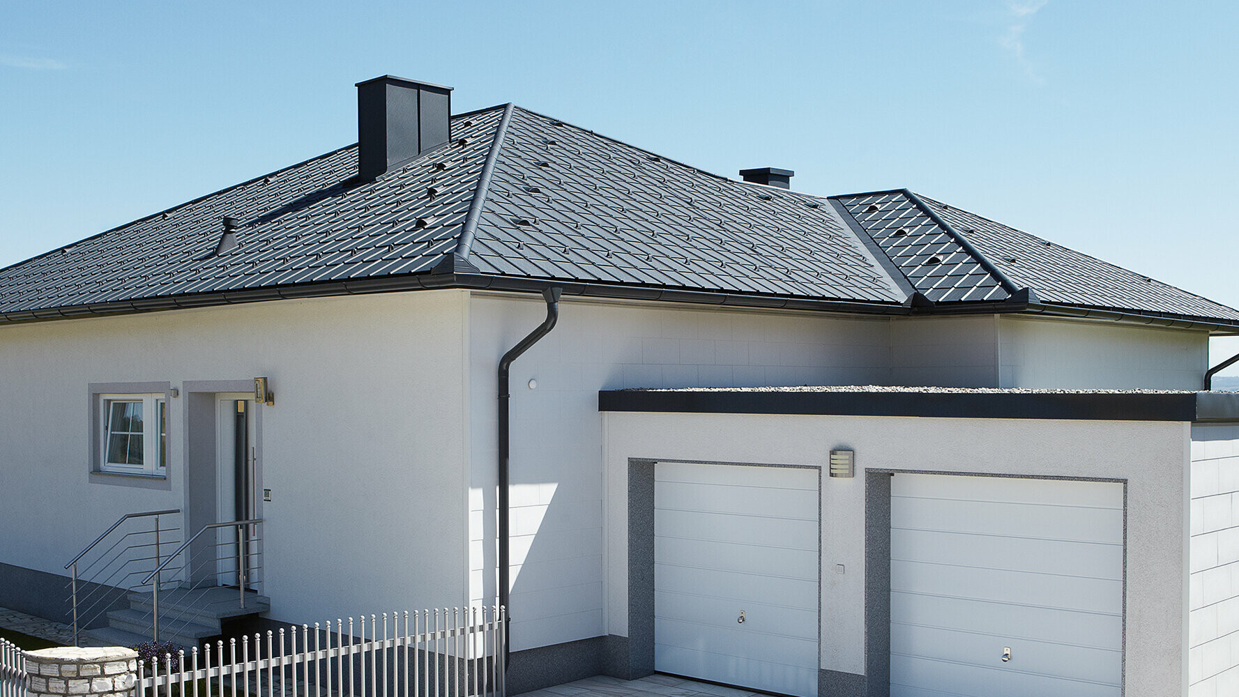 Gerenoveerde bungalow met schilddak en PREFA dakpan in antraciet. Ernaast staat een dubbele garage.