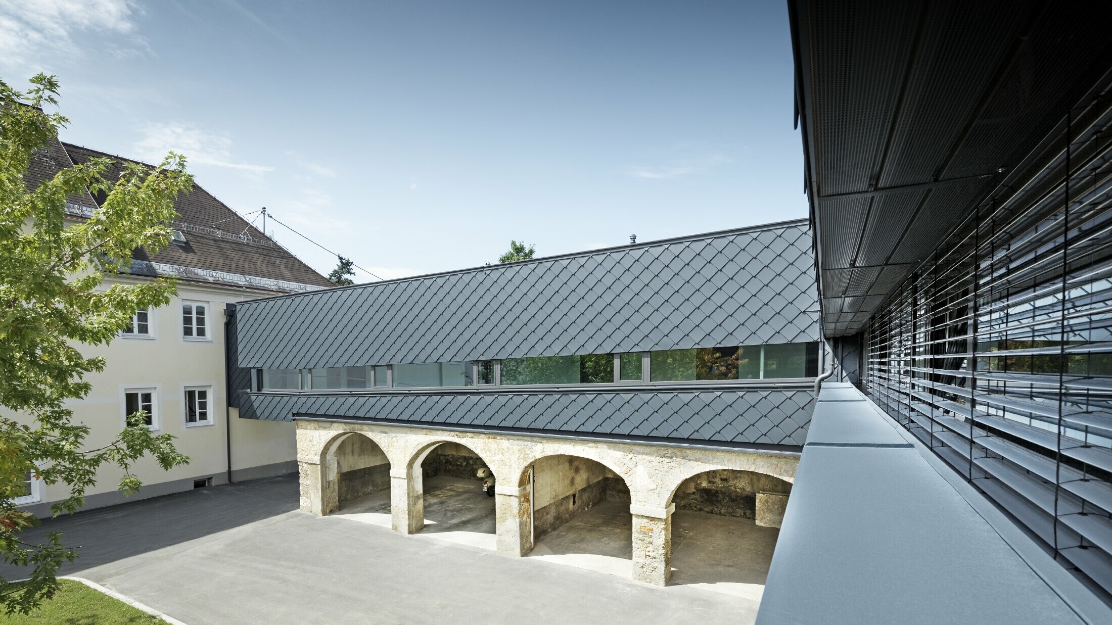 Historisch beschermd gebouw waarvan de verdieping bekleed werd met PREFA gevellosanges 29 in antraciet. Daardoor harmoniëren de oude structuren op de benedenverdieping perfect met de nieuwe losanges.