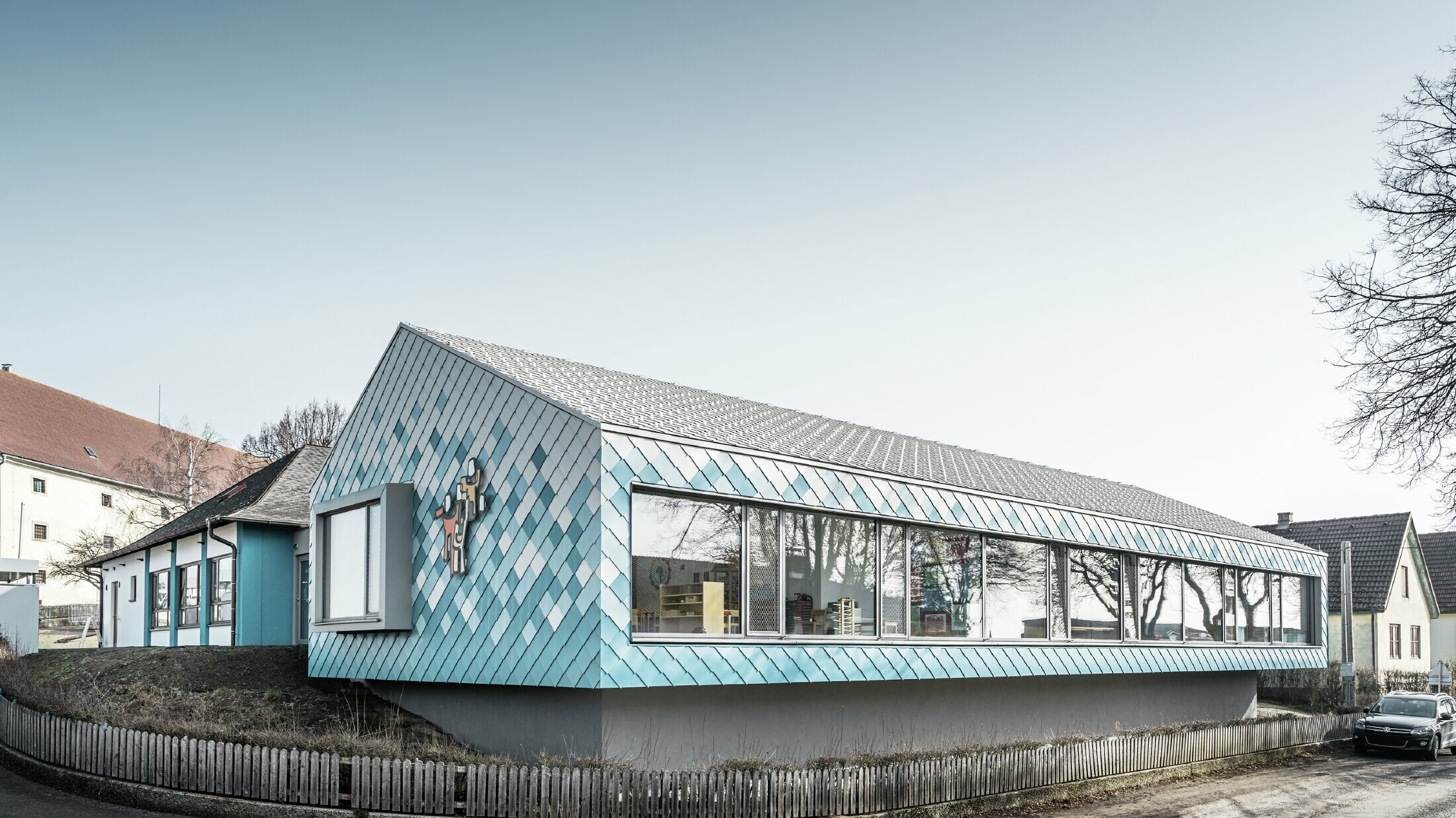 Voor de gevelbekleding van de kleuterschool werd er gekozen voor de PREFA aluminium gevellosange 29 in de kleuren zuiver wit, lichtblauw en turquoise. Die werden zo geplaatst om een kleurverloop te creëren (onderaan blauw, bovenaan wit).