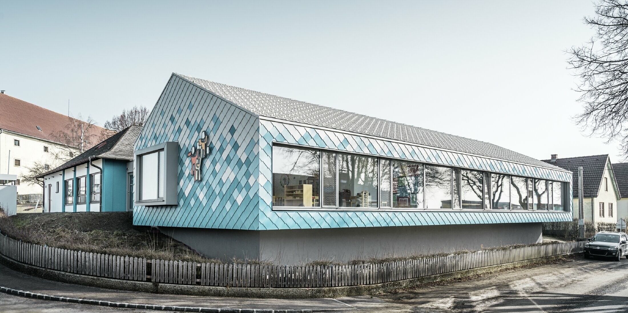 Voor de gevelbekleding van de kleuterschool werd er gekozen voor de PREFA aluminium gevellosange 29 in de kleuren zuiver wit, lichtblauw en turquoise. Die werden zo geplaatst om een kleurverloop te creëren (onderaan blauw, bovenaan wit).