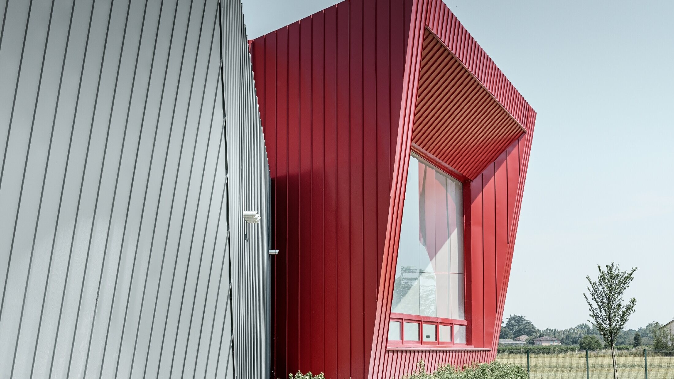 modernes Trainingscenter von Dieci in Montecchio Emilia, Italien, mit Tribüne mit Aluminiumfassade mit Prefalz in hellgrau und Falzonal in karminrot 