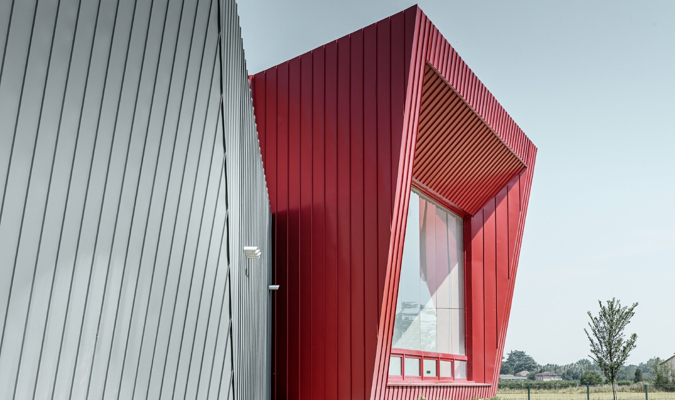 Centre d'entraînement moderne de Dieci à Montecchio Emilia, en Italie, avec tribune revêtue d'une façade en aluminium, avec Prefalz couleur gris souris et Falzonal couleur rouge carmin 
