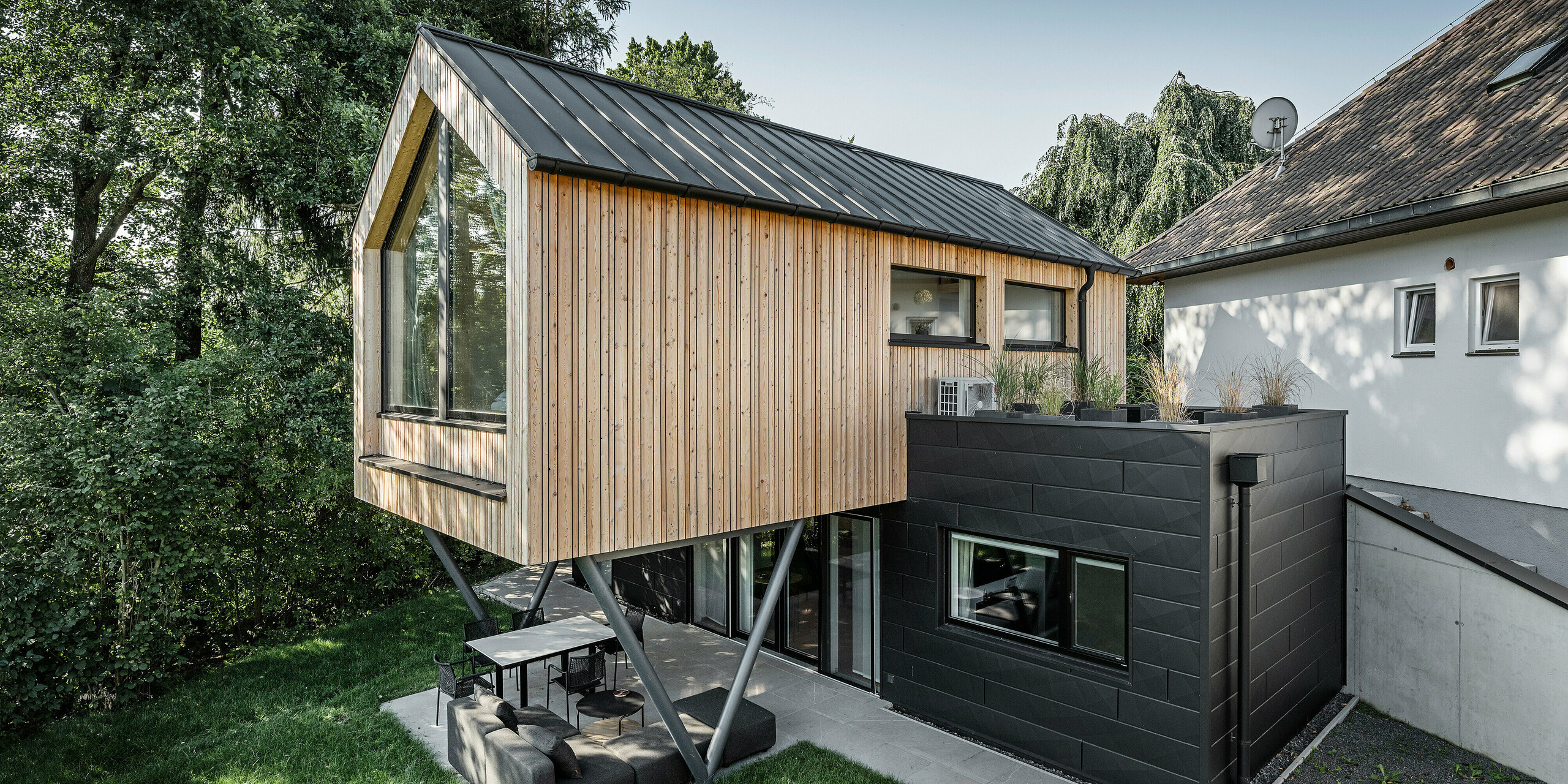 Seitliche Ansicht auf Chalet 5 mit PREFALZ Satteldach, Holz- und PREFA Aluminiumfassade aus Siding.X