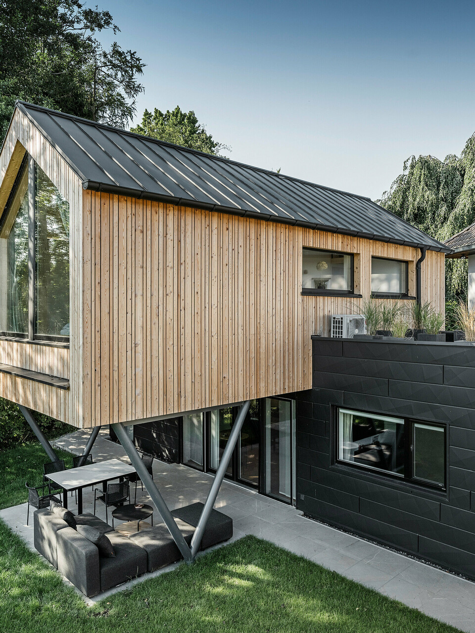 Seitliche Ansicht auf Chalet 5 mit PREFALZ Satteldach, Holz- und PREFA Aluminiumfassade aus Siding.X