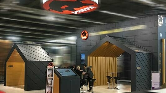 PREFA Messestand mit Messewänden in P.10 schwarzen Siding.X und Rauten und Falzonal in Savannenbeige.