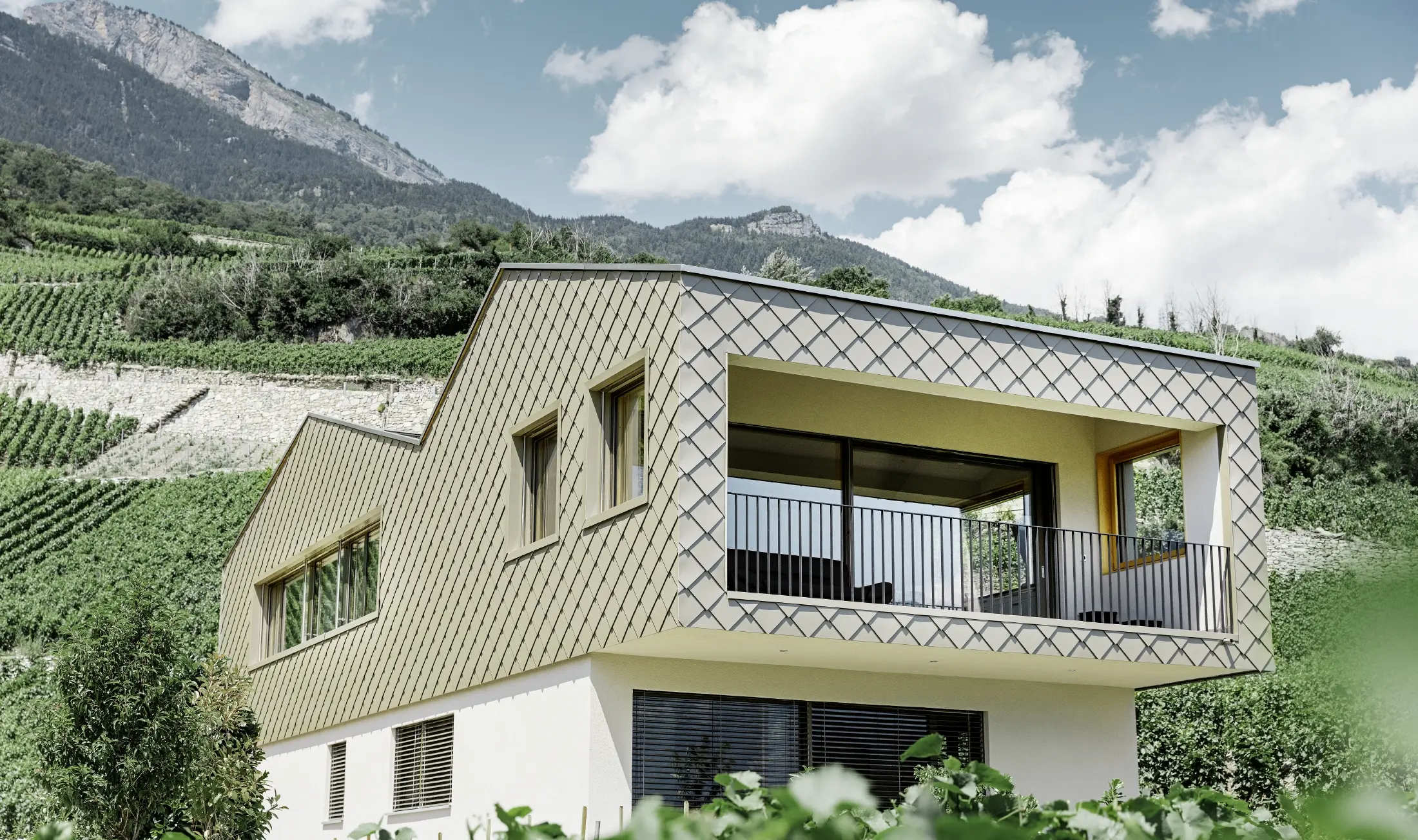 Maison individuelle moderne au cœur des vignobles de la vallée du Rhône avec quatre pentes de toit et grand balcon couvert — Façade habillée de losanges PREFA de couleur bronze