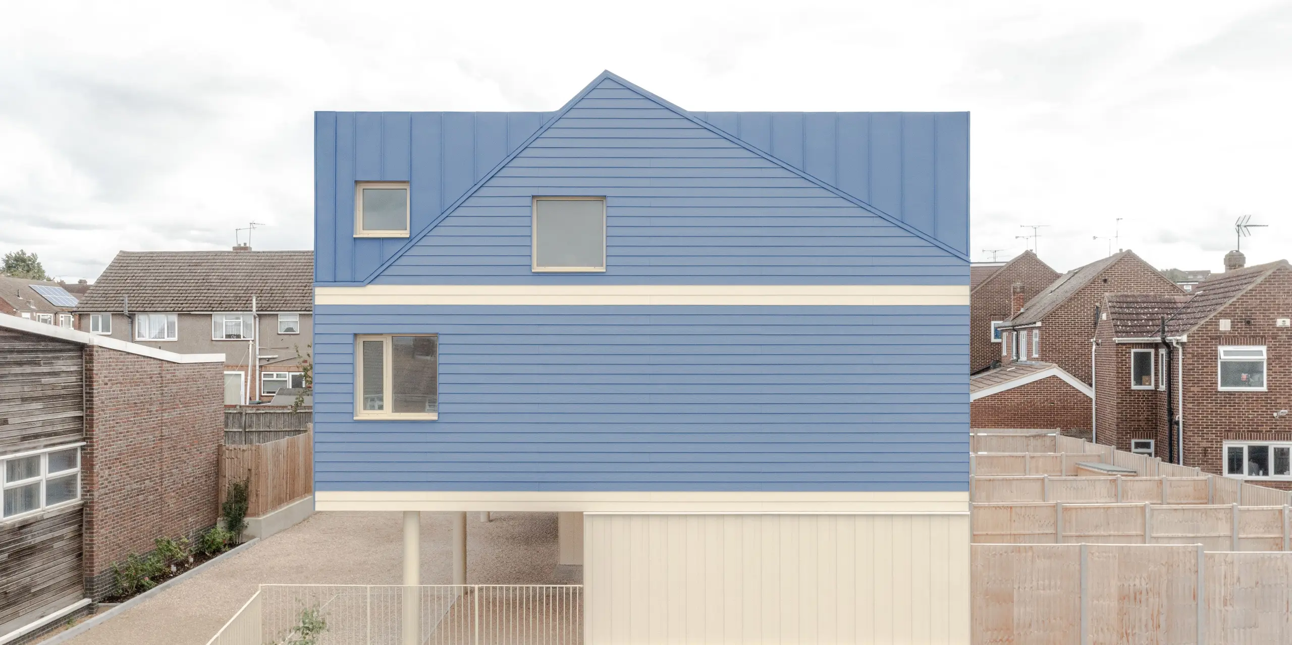 L'image révèle la remarquable toiture et façade en FALZONAL bleu tourterelle du complexe résidentiel Goldsmith Mews, qui se distingue nettement des bâtiments environnants. La précision des joints debout confère à la surface de l'aluminium profondeur et rythme, tandis que la clarté des rez-de-chaussée crée un contraste saisissant et moderne. La construction surélevée paraît légère et aérée. L'aluminium PREFA, robuste et inaltérable, offre une protection durable contre les intempéries, une grande stabilité dimensionnelle et permet une architecture affirmée et audacieuse qui confère à l'ensemble un caractère unique.