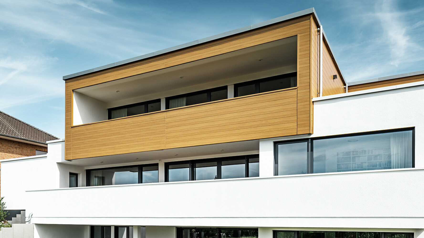 Modernes Wohnhaus mit Erker, der mit PREFA Sidings in der Farbe beige-grau verkleidet ist.