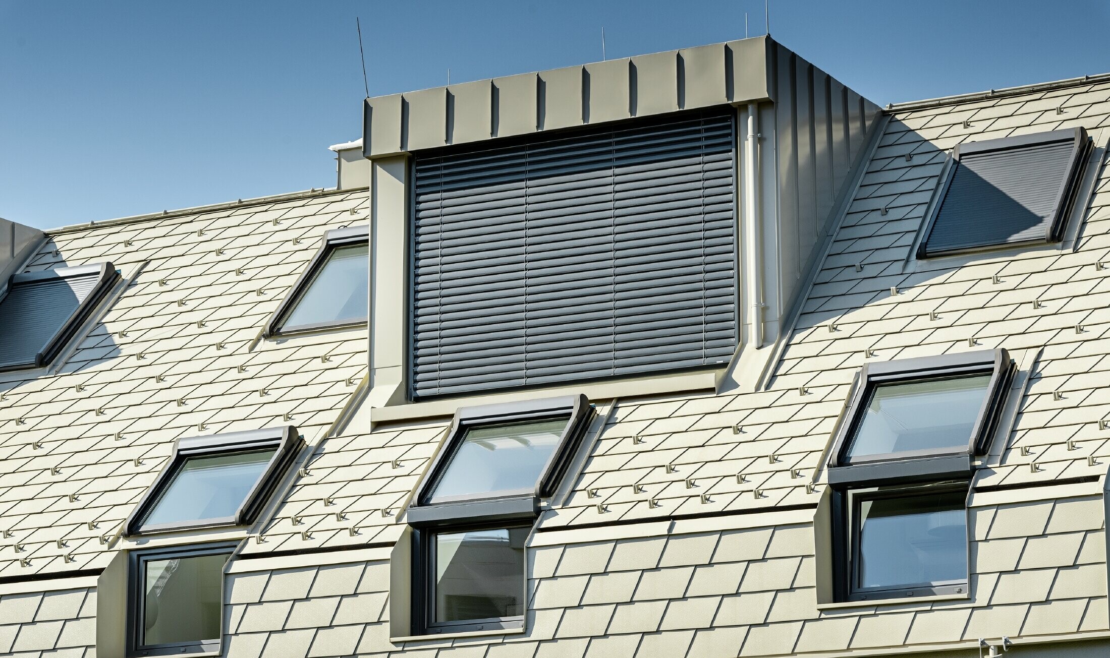 Nieuw woongebouw met groot aluminium dakvlak en talrijke dakvensters