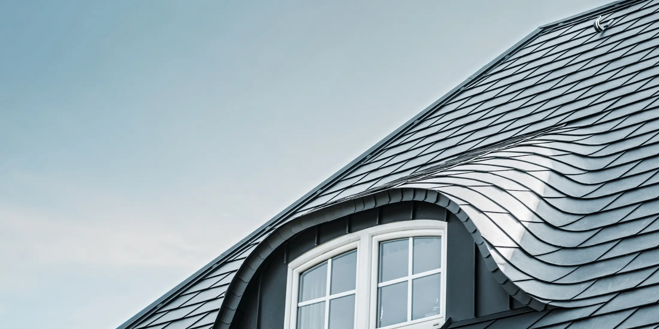 Toit rénové avec lucarne arrondie avec fenêtre, recouverte de bardeaux en aluminium PREFA en P.10 anthracite 