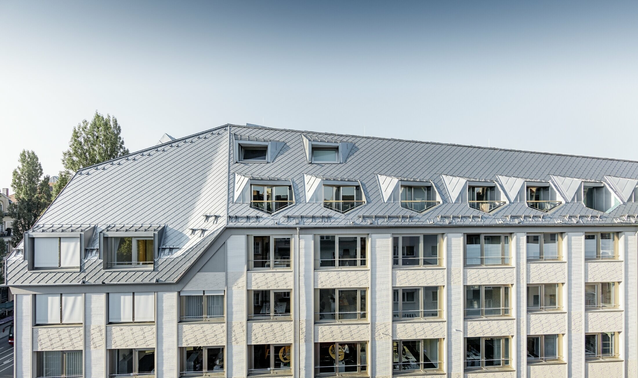 Sanierte Mansardenwohnungen mit großzügigen offenen Galerieebenen eines Wohn- und Geschäftshauses in der Leopoldstraße/Ecke Hohenzollernstraße in München, mit einer Dacheindeckung von PREFA - Dachraute