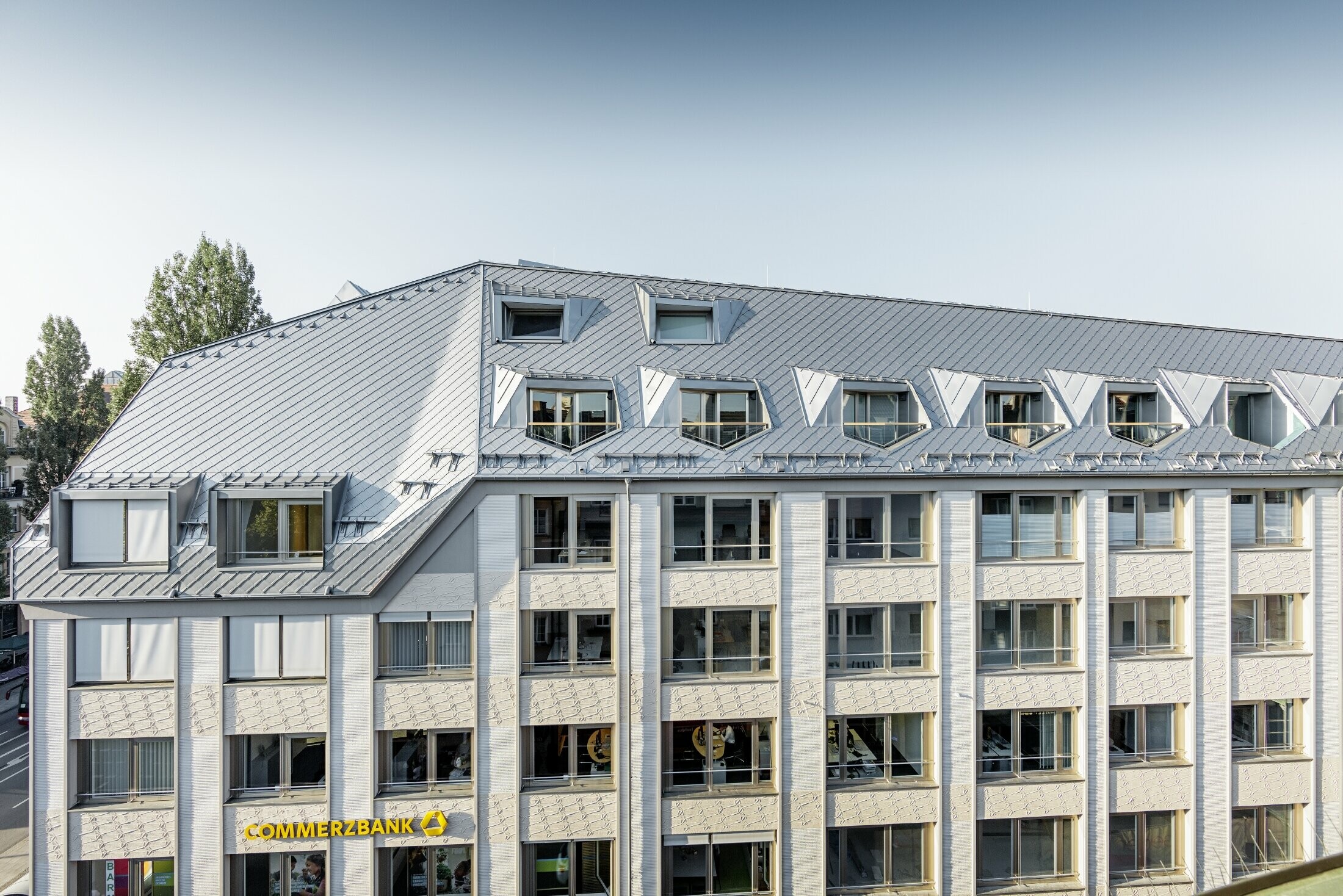 Appartements mansardés rénovés et dotés de spacieuses mezzanines, aménagés dans un immeuble d’habitation et de commerces munichois de la Leopoldstraße, à l’angle de la Hohenzollernstraße — Couverture de toit réalisée avec des losanges de toiture PREFA