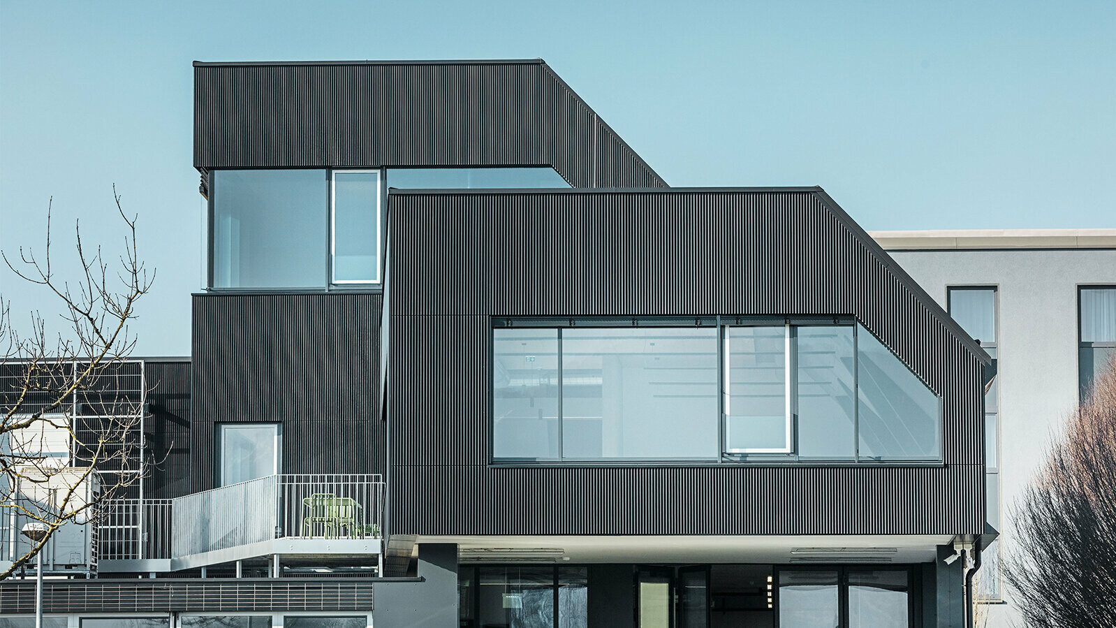 Zijaanzicht van het gebouw van Amann Kaffee op een zonnige dag Ter bescherming van het gebouw werd een gekarteld profiel in de kleur zwart gebruikt.