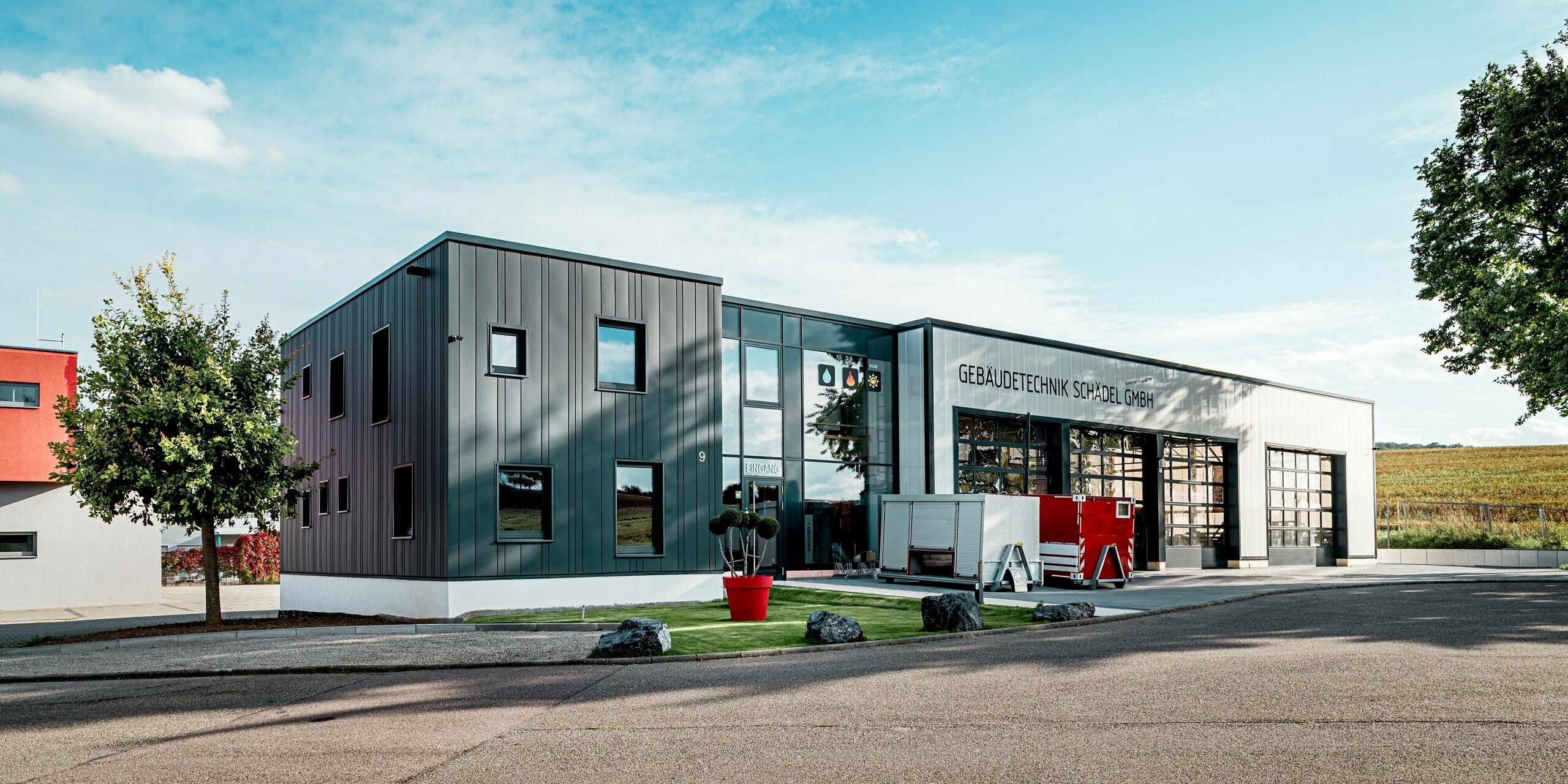 Aus der Perspektive der Zufahrt wirkt das Firmengebäude der Gebäudetechnik Schädel GmbH besonders imposant. Die anthrazitfarbenen PREFA Sidings erzeugen eine klare, strukturierte Optik, die perfekt zur modernen Industriearchitektur passt. Die Kombination mit der hellen Sockelzone und der großen Glasfront schafft starke Kontraste. Die witterungsbeständigen Aluminiumprofile sorgen für langanhaltende Ästhetik und Schutz.