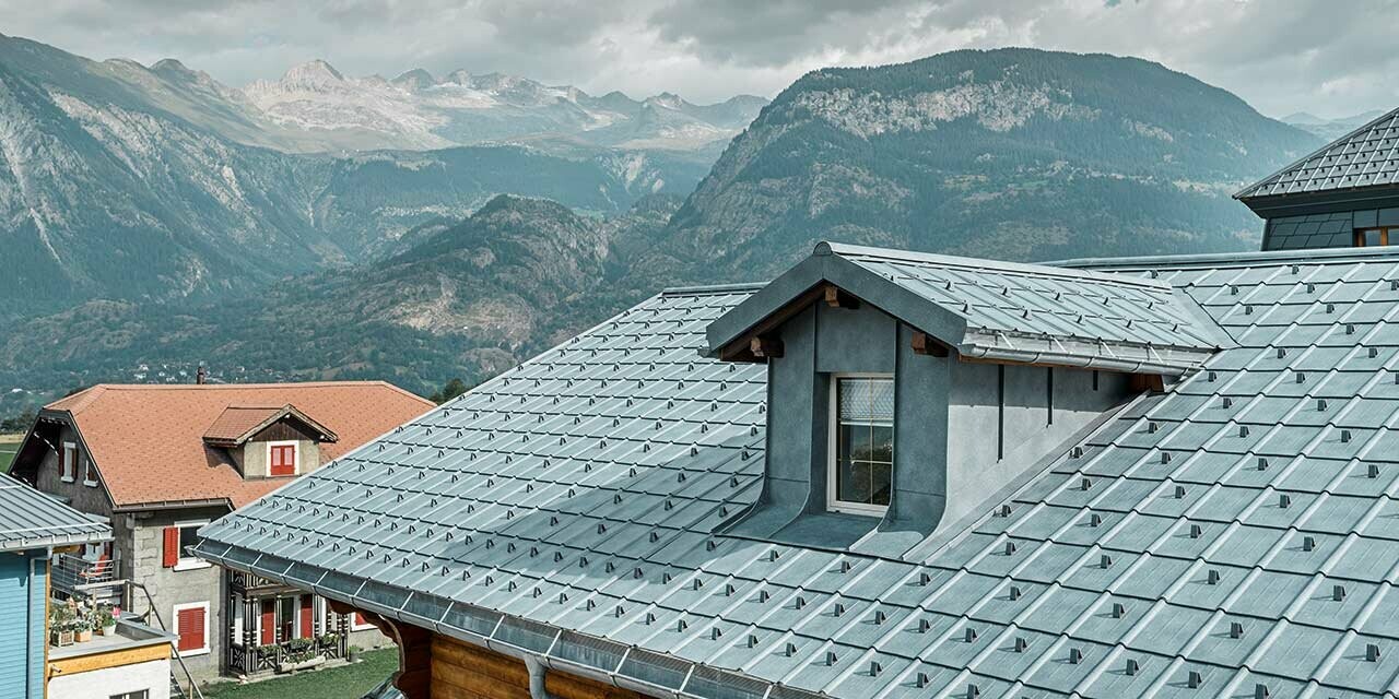 Zadeldak met dakkapel; op het dakvlak is het metalen dak van PREFA gelegd - de dakpan is in steengrijs. De dakkapel is bekleed met de haakse staande fels van PREFA in steengrijs.