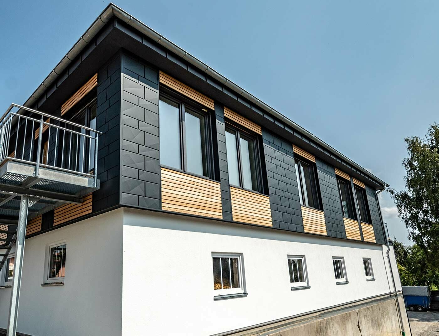 La partie haute du bâtiment a été recouverte à la fois de panneaux de mélèze posés à l’horizontale et de panneaux Siding.X PREFA en aluminium couleur anthracite.