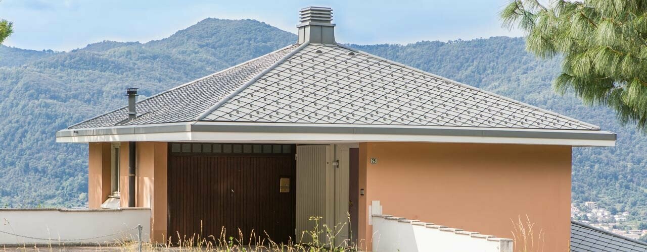 Bâtiment d’habitation orange avec toit en pavillon couvert de losanges de toiture 29 × 29 PREFA couleur P.10 gris souris.