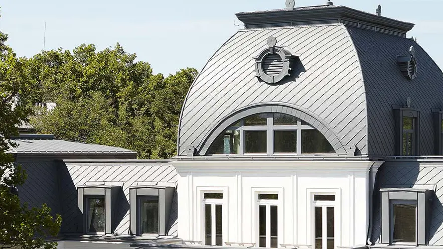 Mansarddach mit Kuppel des denkmalgeschützten Gebäudes saniert mit PREFA Dachrauten und Prefalz in P.10 Hellgrau