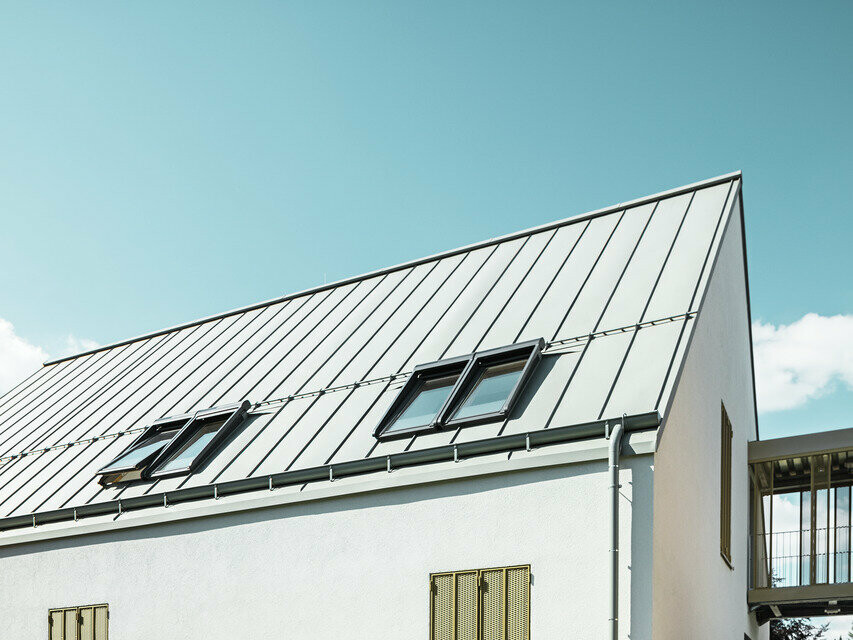 Vue arrière du foyer d'Augsburg, on aperçoit la toiture en PREFALZ dans la teinte P.10 gris de zinc ensoleillée 