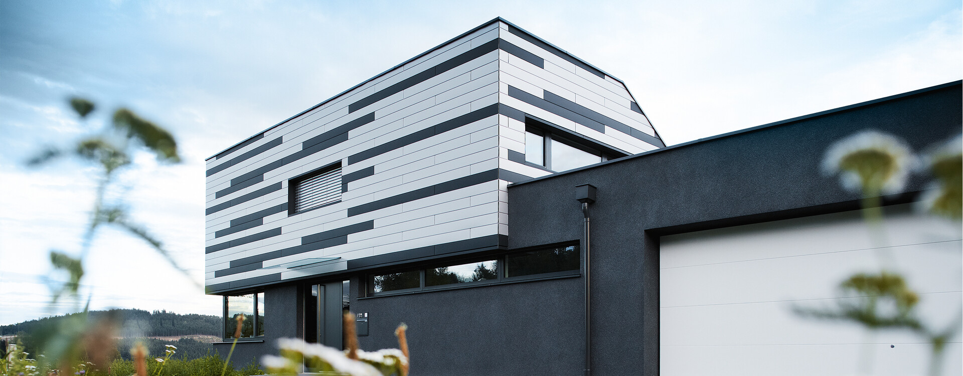 Modernes Einfamilienhaus mit kreativer Fassadengestaltung; Die PREFA Sidings wurden in Silber und Anthrazit matt gemischt verlegt.