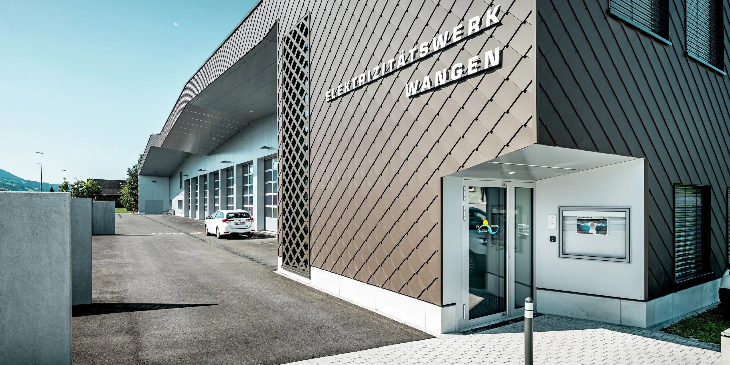 Markante Fassadenansicht des Elektrizitätswerks und der Feuerwehr in Wangen, Schweiz. Die PREFA Wandrauten 29 × 29 in P.10 Braun verleihen dem Gebäude mit ihrer präzisen Rautenstruktur eine außergewöhnliche Tiefenwirkung. Helle Aluminium Verbundplatten in Prefaweiß setzen moderne Akzente. Die langlebigen Aluminiumfassaden überzeugen durch Witterungsbeständigkeit, geringen Wartungsaufwand und eine ausdrucksstarke Architektur.