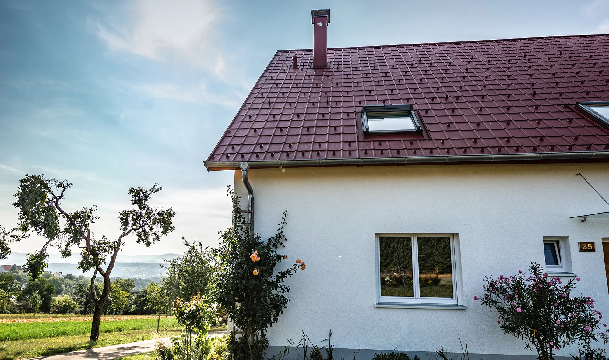 Maisonnette à la campagne, toiture rénovée avec tuile PREFA couleur rouge oxyde, fenêtres de toit et abergement de cheminée.