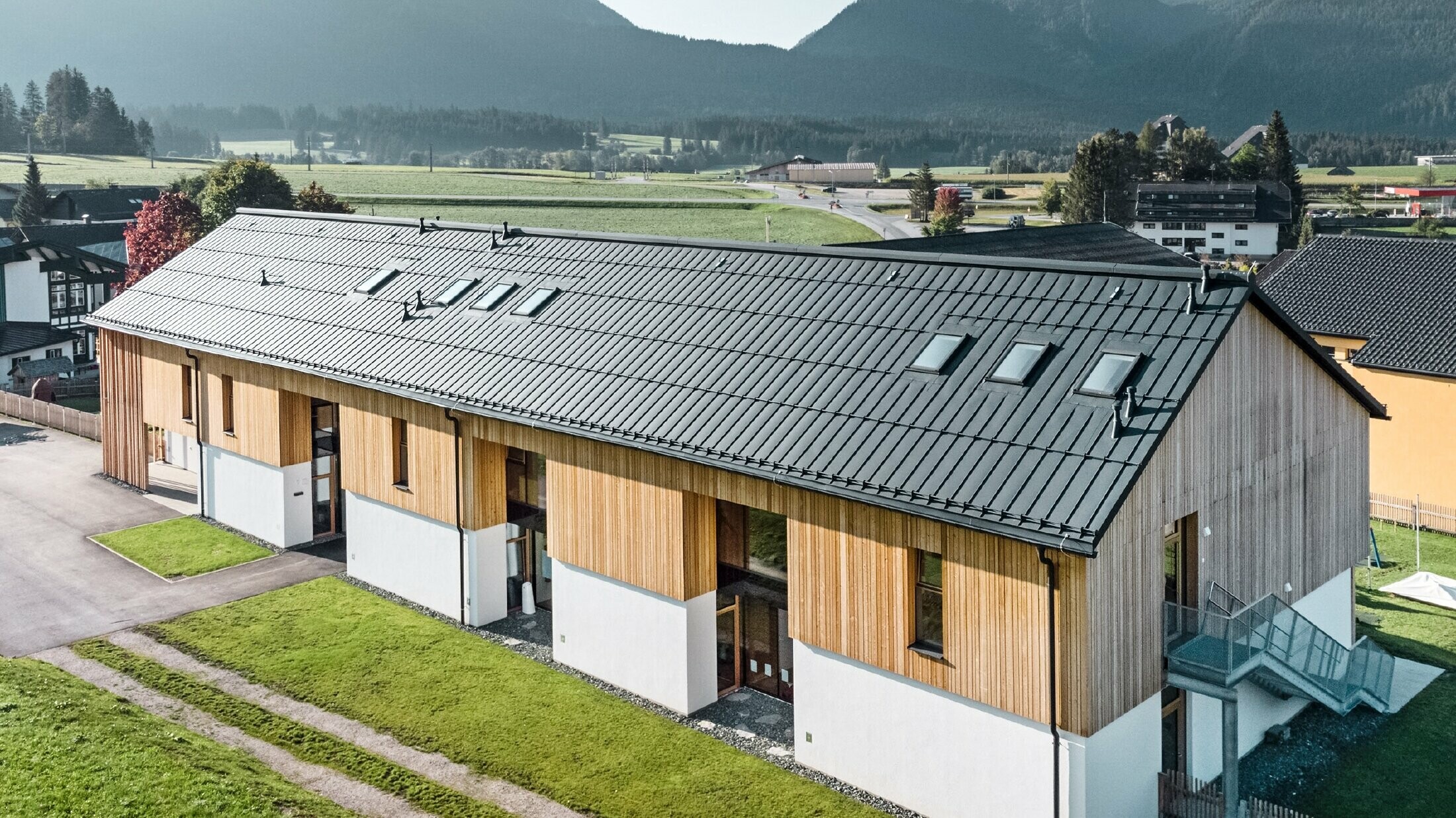 Kruidenkleuterschool in Bad Mitterndorf met groot PREFALZ dak in P.10 antraciet en houten gevel