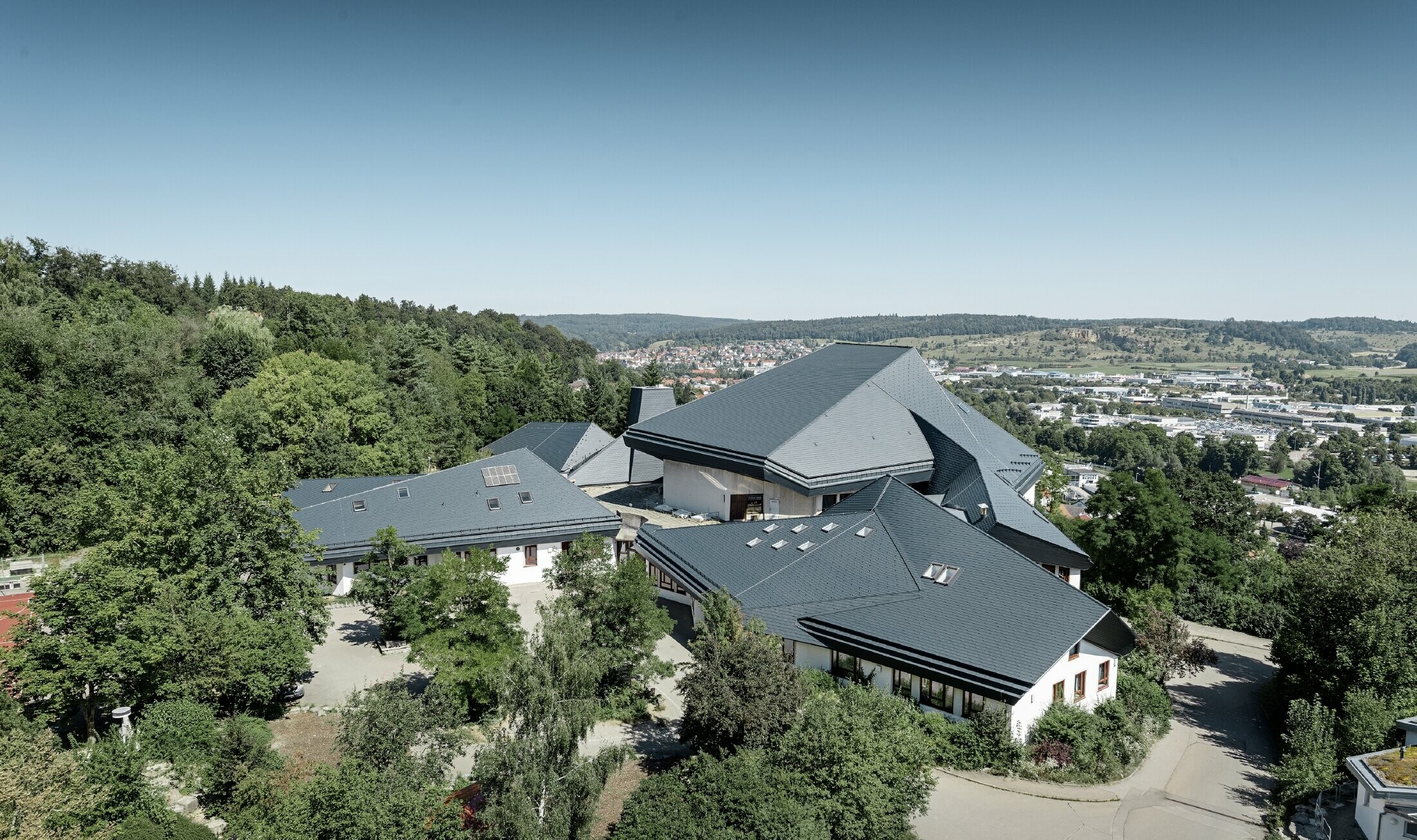 Vrije school in Heidenheim (Duitsland) met groot en onregelmatig dakvlak gerenoveerd met PREFA-dakschindels in antraciet