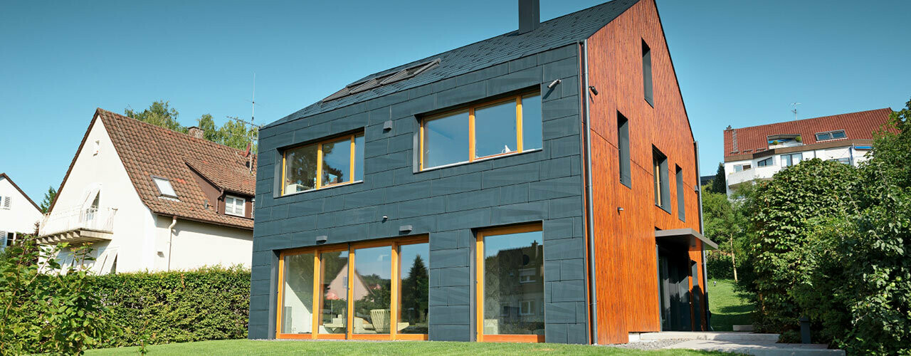 La façade en FX.12 PREFA couleur P.10 anthracite se prolonge sur le toit à deux pans, sans avancée de toit.