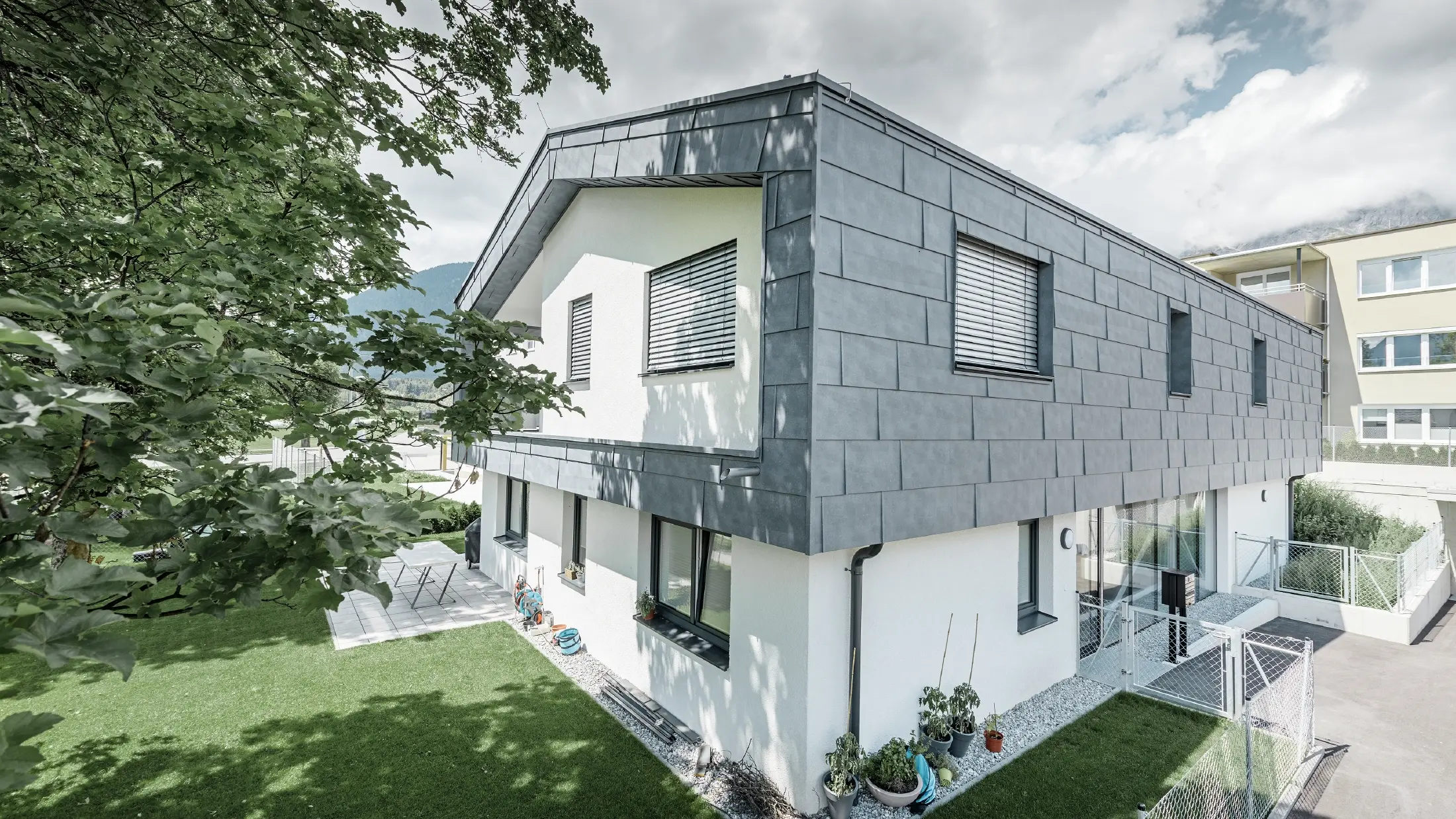Moderne verhoging van een woonhuis met plat zadeldak en zonder dakoverstek; De gevelbekleding is uitgevoerd met het PREFA gevelpaneel FX.12 in steengrijs.