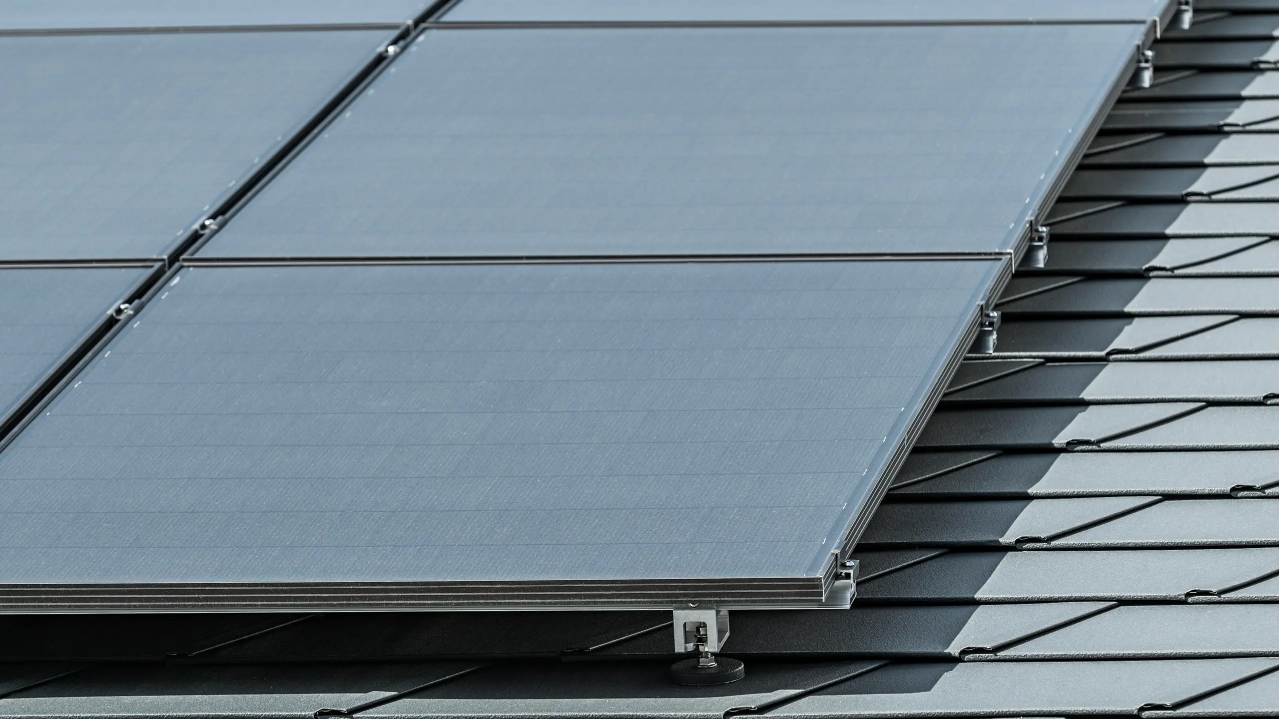 Close-up van een fotovoltaïsch systeem gemonteerd op PREFA dakshingles DS.19 in P.10 antraciet met PREFA Solar Holder Vario