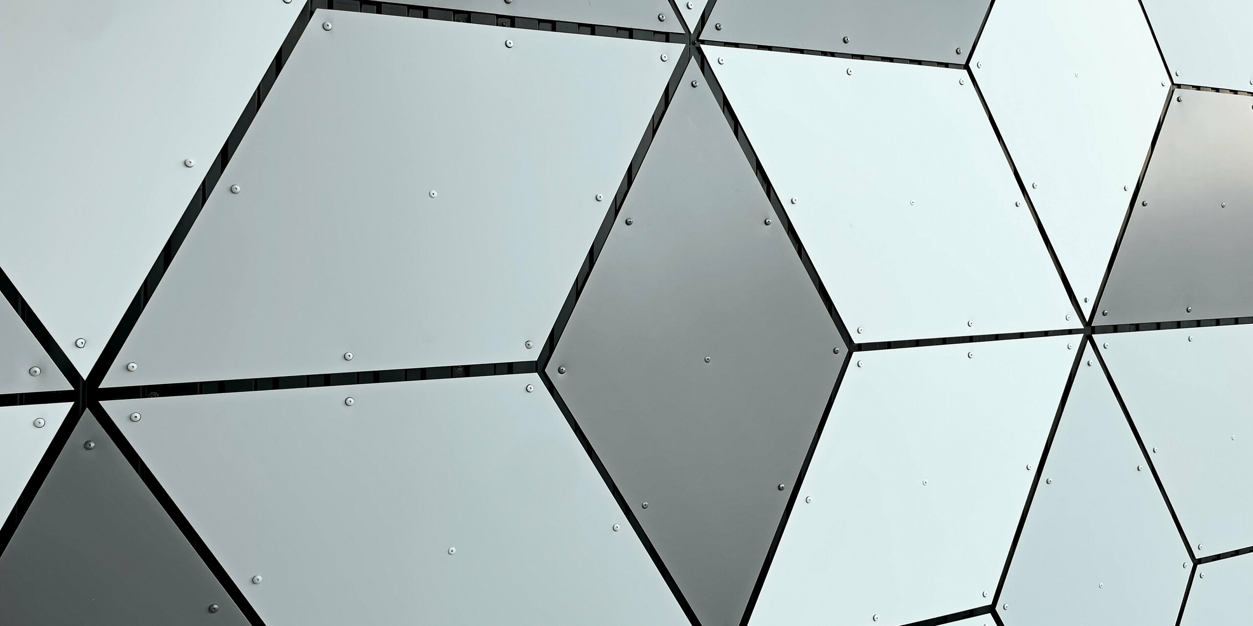 Vue détaillée de la façade de la station de téléphérique des Deux Alpes. Les panneaux composites en aluminium PREFABOND sont disposés en losange. L'association fascinante de tons blancs et gris crée un motif géométrique moderne. La fixation par vis robuste souligne la robustesse et la résistance de la construction, capable de résister aux conditions climatiques extrêmes de la haute montagne.