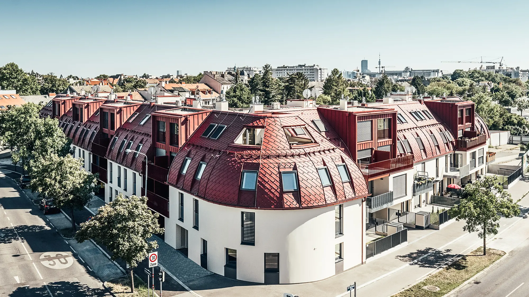 Straatbeeld van het wooncomplex Schöneck 13 en het afgeronde daklandschap, ontworpen door architectenbureau schneider+schumacher.