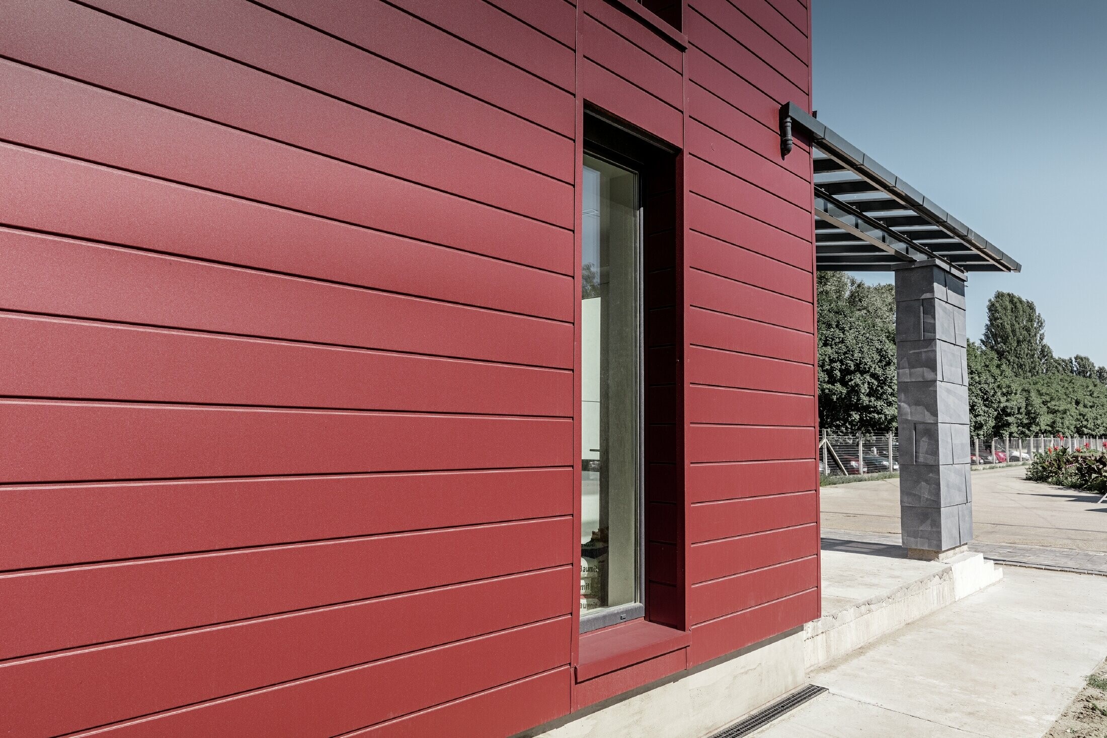 Complexe de bureaux moderne — Façade tricolore (blanc, rouge et gris pierre) réalisée à partir de produits en aluminium PREFA (sidings, panneaux de façade FX.12 et panneaux composites en aluminium)