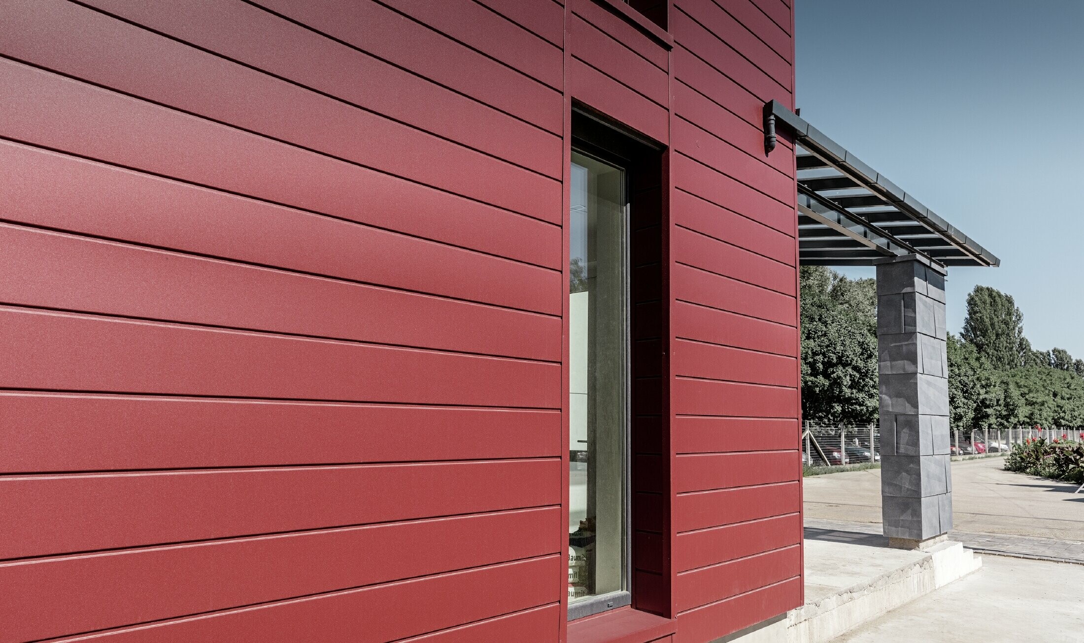 Modern kantoorgebouw met gevel opgebouwd uit 3 aluminiumproducten van PREFA: rode sidings, witte composietplaten en FX.12 gevelpanelen in steengrijs