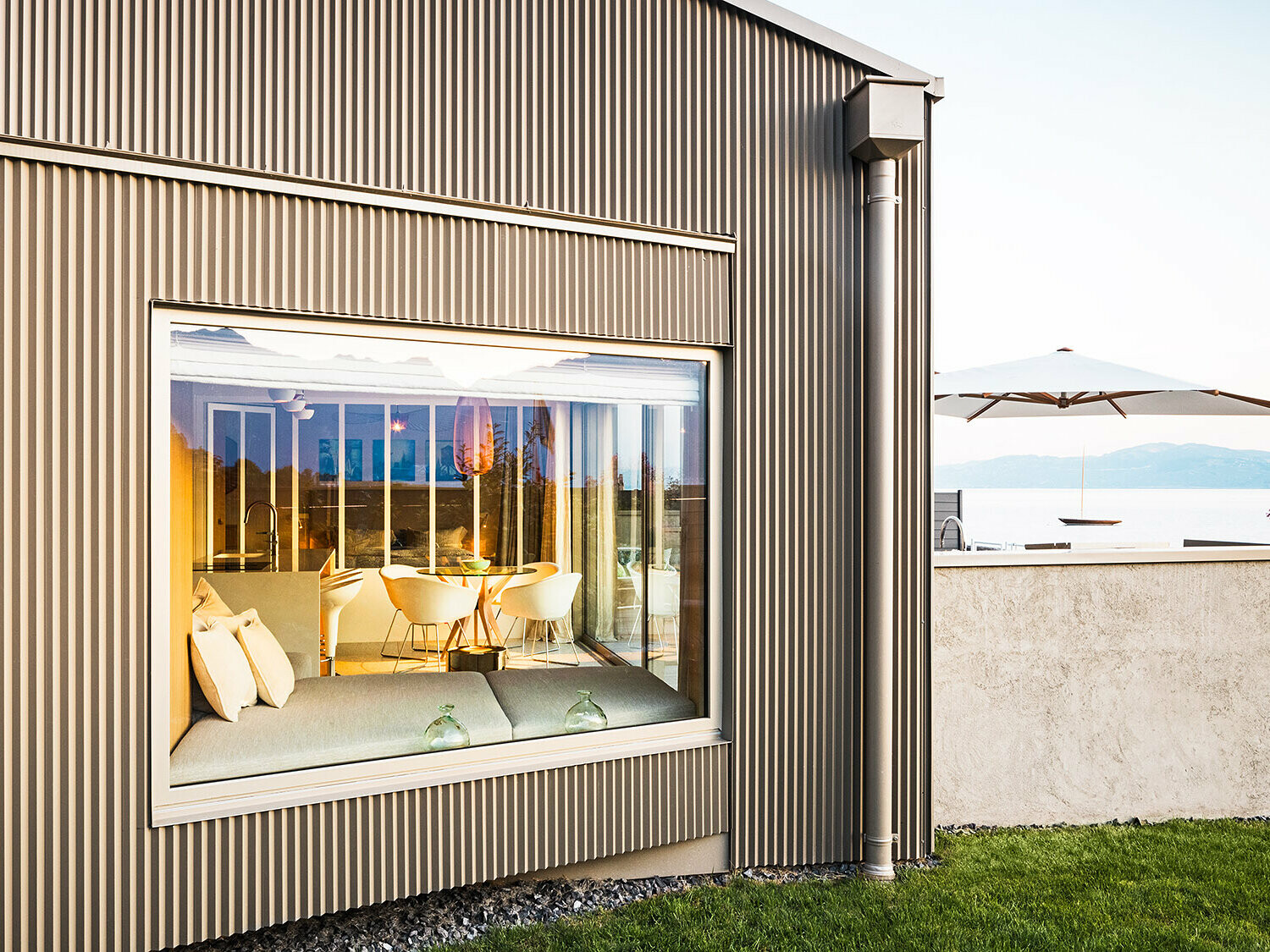 Vue latérale du bâtiment avec une façade en profils triangle aluminium ; une partie de l'intérieur éclairé est également visible.