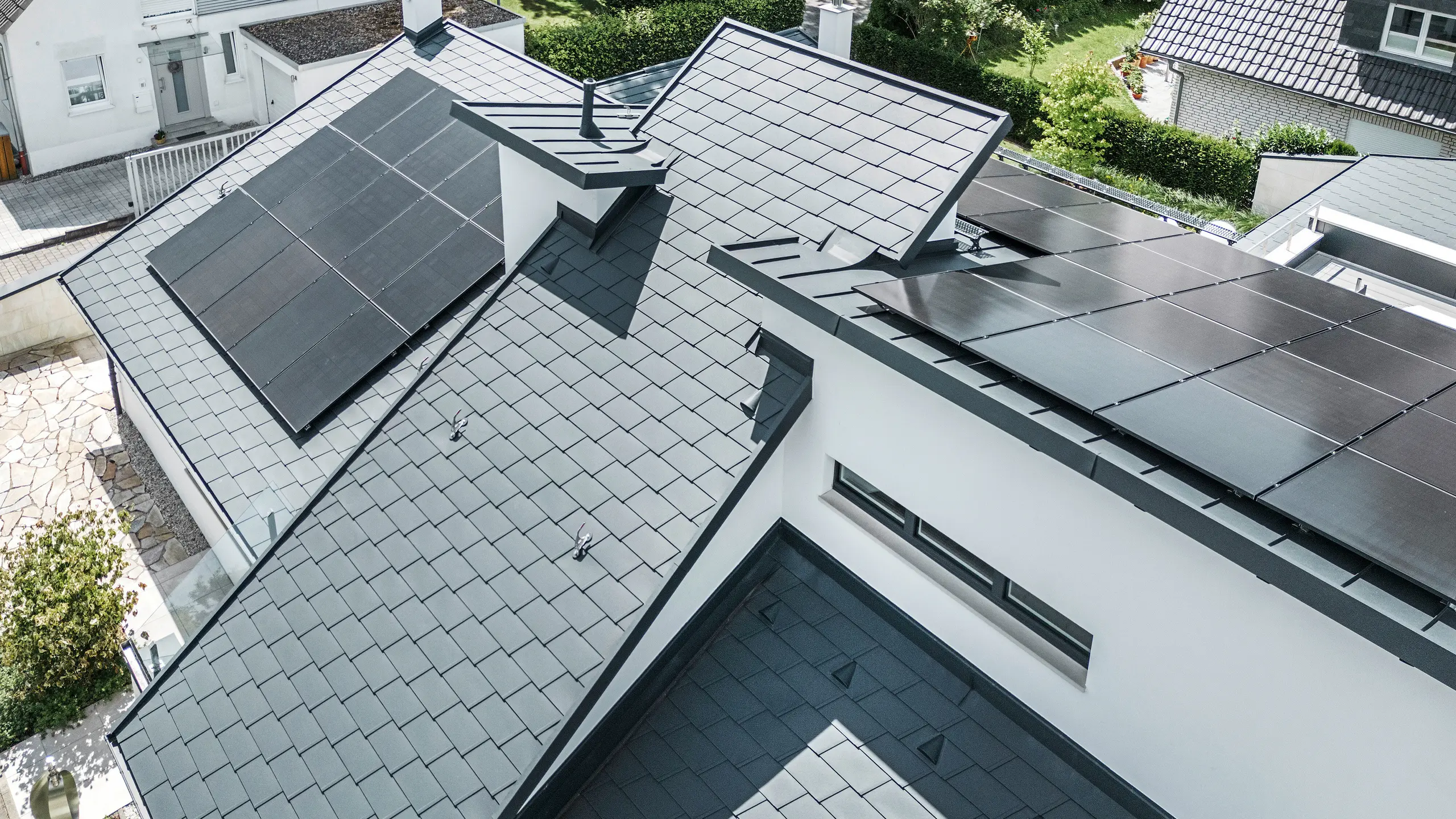 Het dak van een moderne eengezinswoning in Dortmund werd in vogelvlucht voorzien van PREFA DS.19 en PREFALZ dakshingles in de kleur P.10 antraciet en een grootschalige PV-installatie.