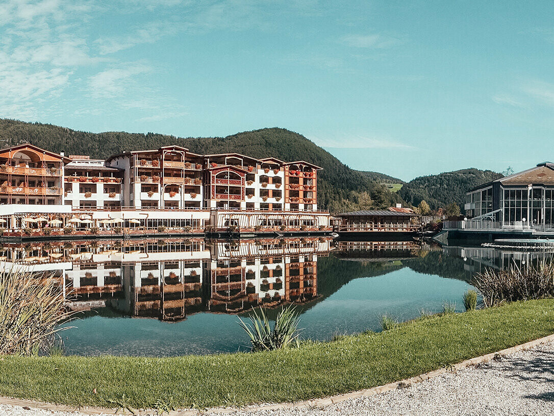 Bild vom Hotel im Tiroler Stil vor dem Umbau, vor dem Hotel liegt ein See