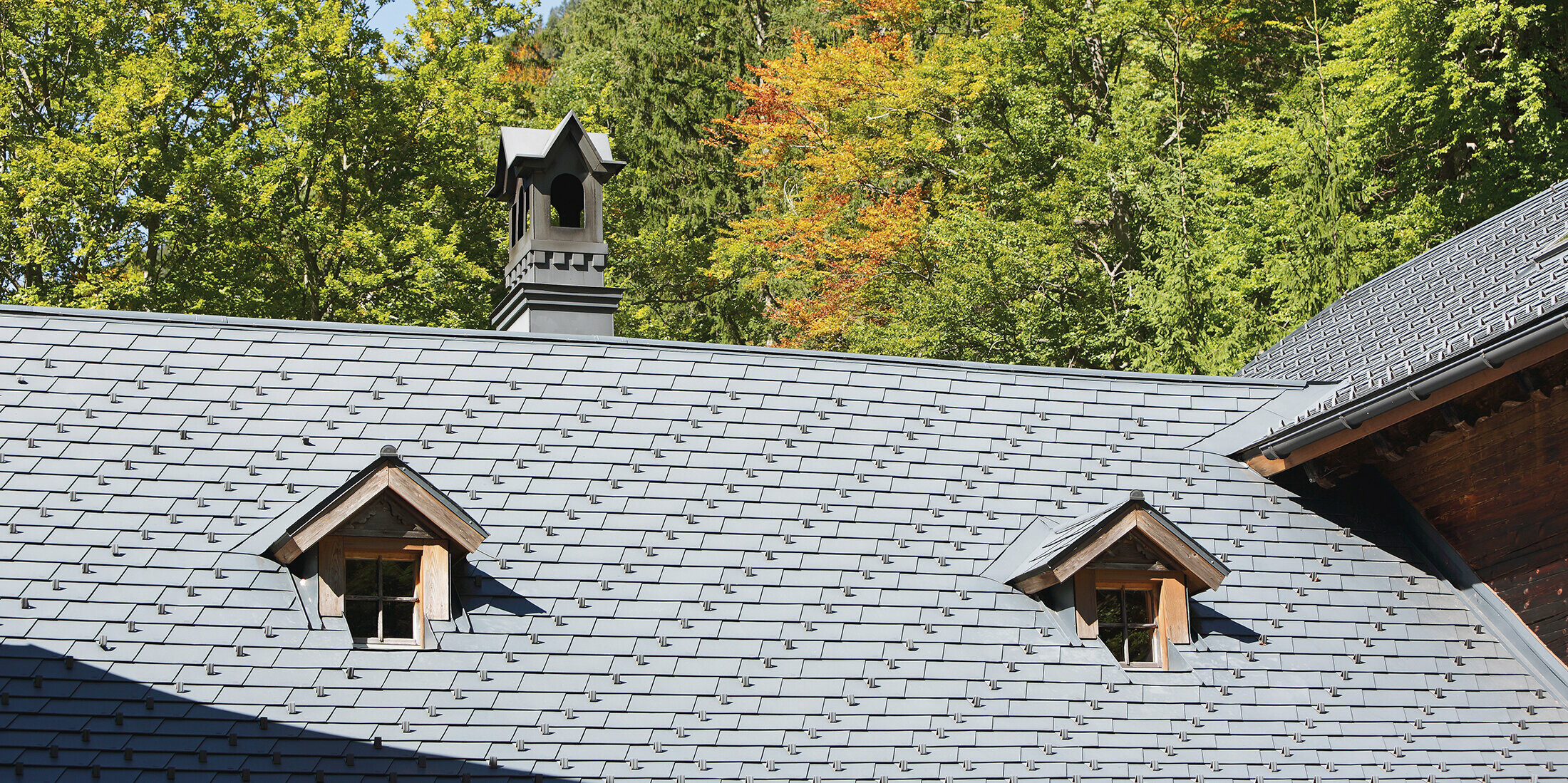 Detailaufnahme des Daches des Rothschildhauses in Langau bei Gaming mit PREFA Dachschindeln in Anthrazit, begleitet von traditionellen Architekturmerkmalen und Natur.